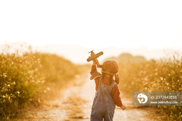 Child pilot aviator with airplane dreams of traveling in summer in nature at sunset