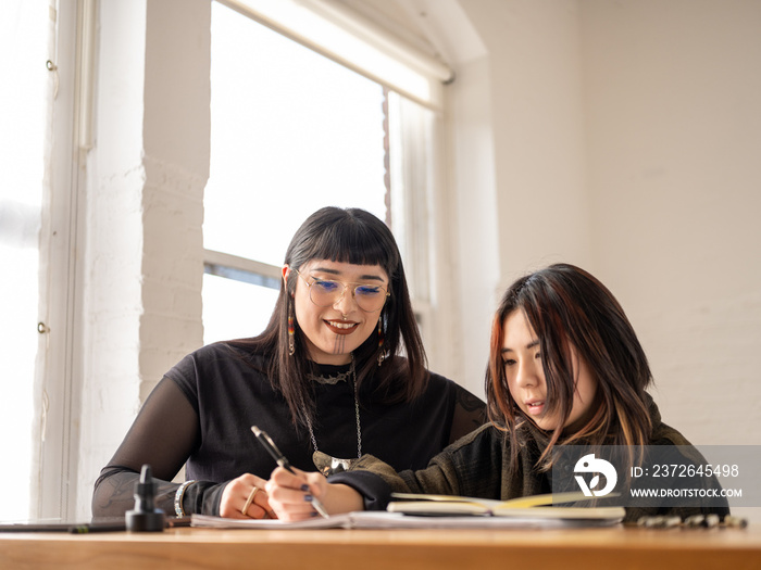 Non binary artist and non-binary student drawing indoors