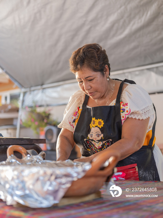 Indigenous woman with apron working in an outdoor kitchen