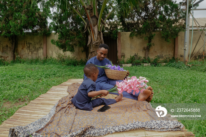 Boy and father wearing traditional sitting at the park