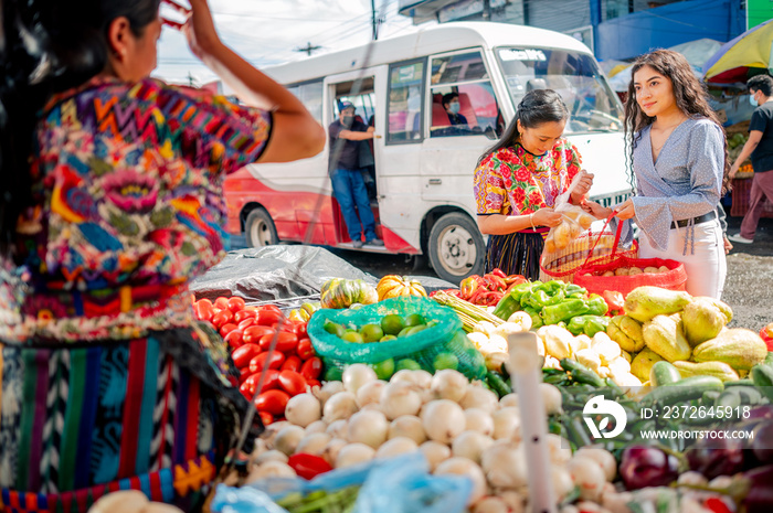 Madre e Hija van al mercado local a comprar vegetales frescos.