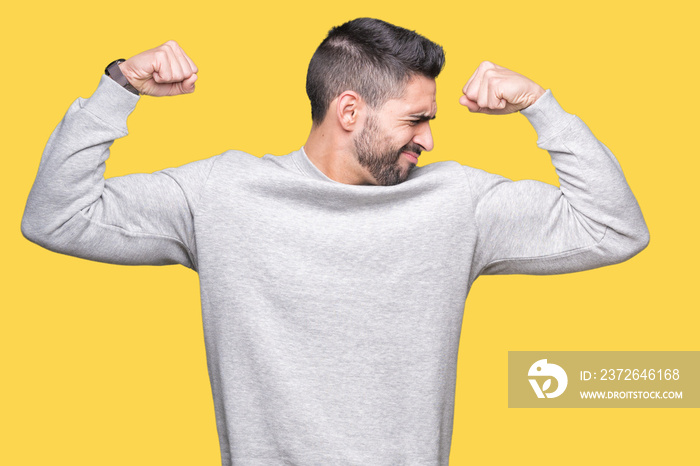 Young handsome man wearing sweatshirt over isolated background showing arms muscles smiling proud. F