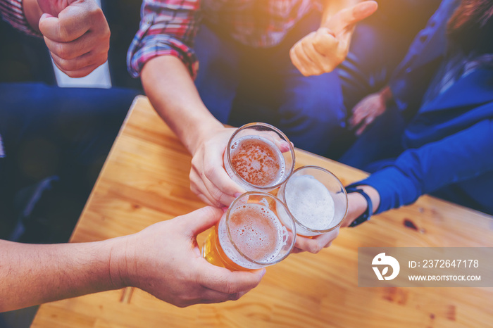 Group of friends clinking the glasses of beer in nightclub. Party after working