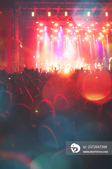 Silhouettes of festival concert crowd in front of bright stage lights. Unrecognizable people and col