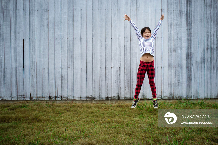 Portrait of girl (6-7) jumping in backyard