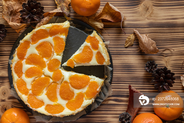 Cheesecake oder Käsekuchen mit fruchtigen orangen Mandarinen auf einem Tisch aus Holz im Herbst mit 