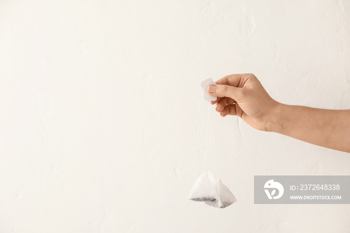 Female hand with tea bags on light background