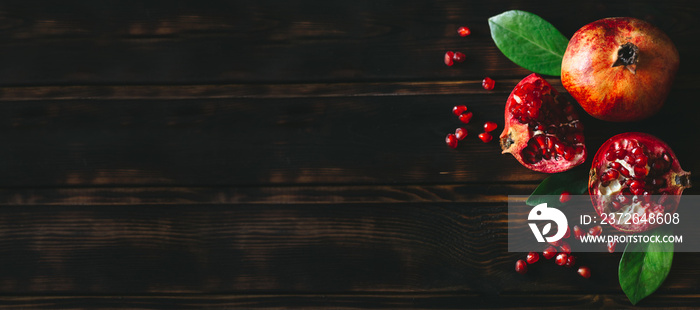 Fresh juicy pomegranate whole and cut, with leaves on a wooden vintage background, top view, horizon