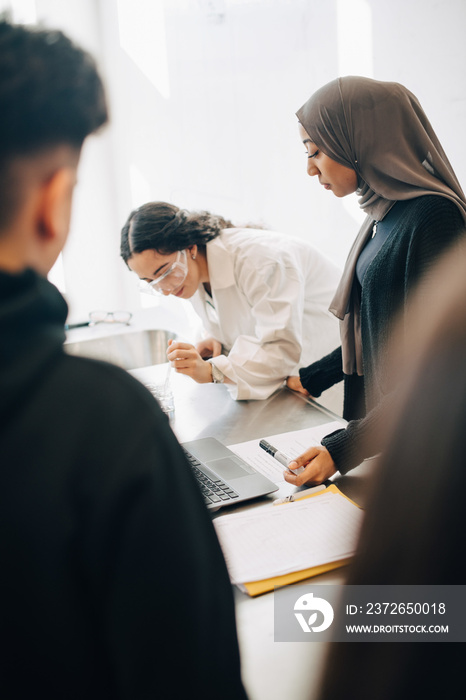 Multi-ethnic students learning scientific experiment in chemistry class