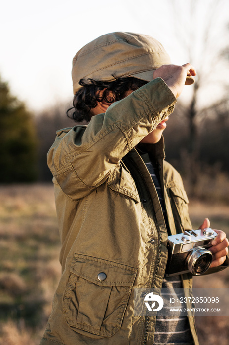 Boy (6-7) with old-fashioned camera standing in meadow