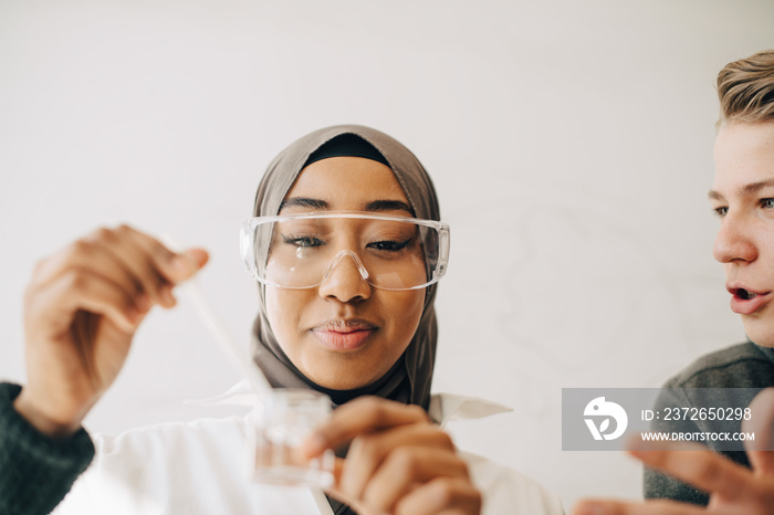 Teenage boy talking to female classmate during experiment in science class