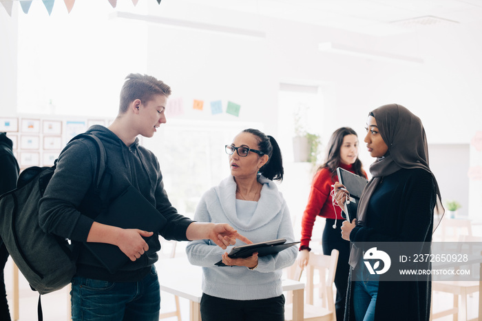 Students discussing with teacher after class at university