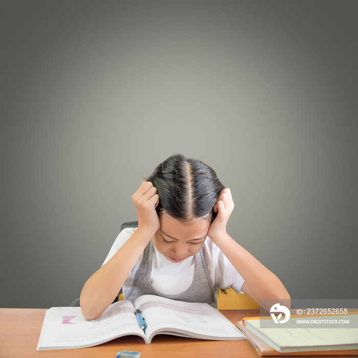 Stressed schoolgirl doing homework and preparing for exams. Young Asian student girl hard at work is