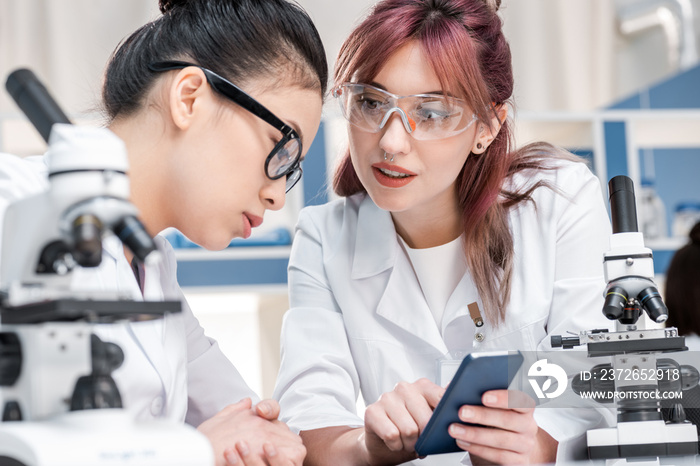 scientists working together with microscopes and smartphone in chemical lab, scientists team concept