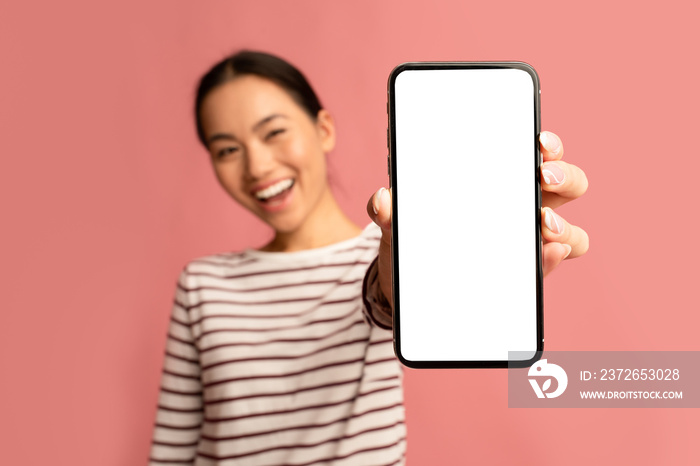 伟大的应用程序。兴高采烈的亚洲女性用空白白屏幕演示智能手机