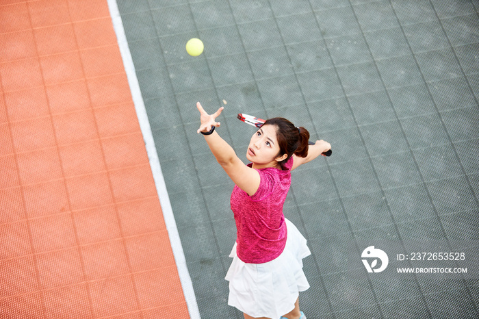 high angle view of young asian girl serving during tennis match