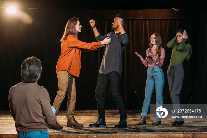 multiethnic actors rehearsing fight on stage in theatre