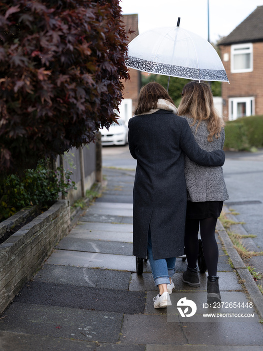 Back view of couple with stroller walking on sidewalk�