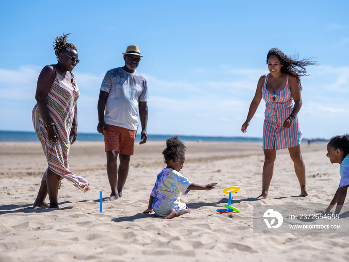 Family with children (2-3, 6-7) playing ring toss on beach