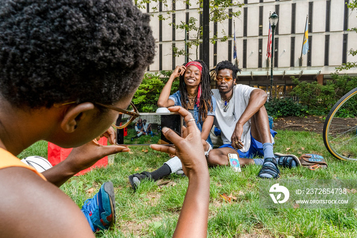 USA, Woman photographing friends sitting on grass