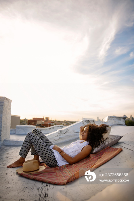 Young woman lying on blanket on rooftop