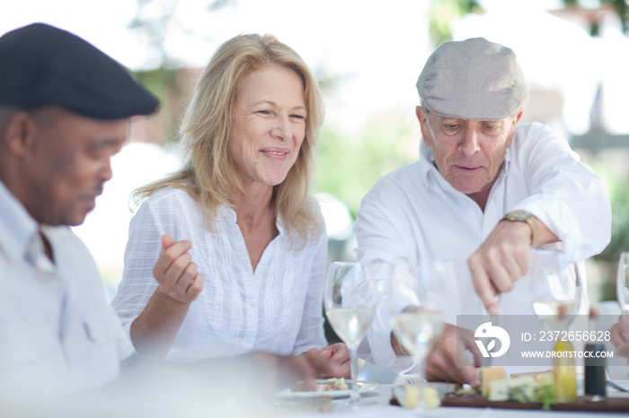 Older friends eating together outdoors