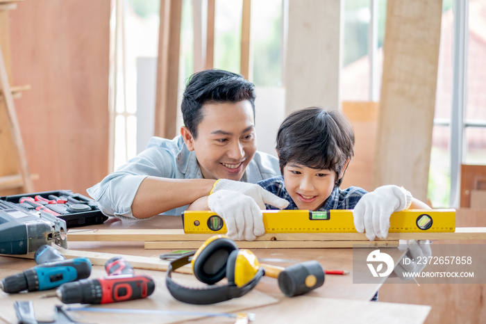 亚洲父亲教儿子用to来测量和调整家里的木制品水平。Co