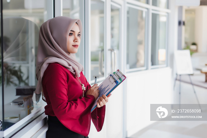 Young asian muslim woman teacher holding documents and learning plan.