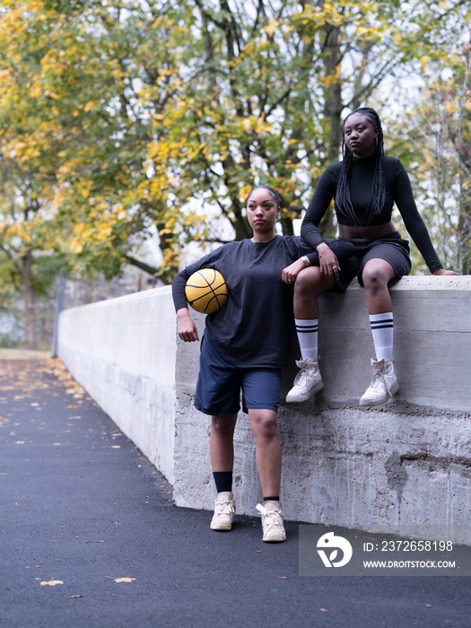 Two female friends outdoors holding basketball ball