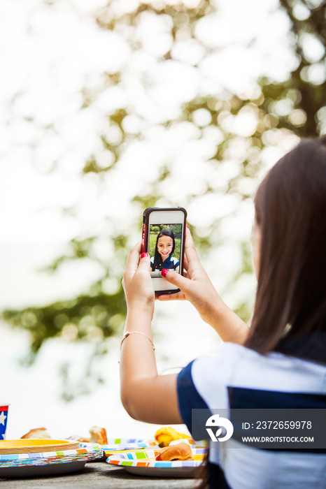 Girl taking selfie at table outdoors