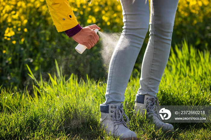 Spraying insect repellent on legs and boots. Protection against tick