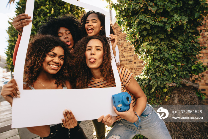 Young women posing with blank picture frame