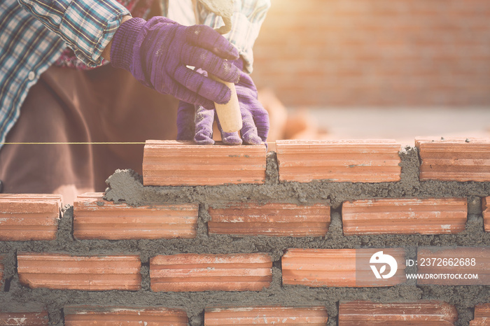 Worker installing bricks wall in process of house building