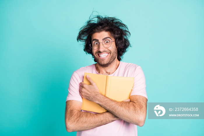 Photo of weird hairstyle satisfied man arms hold cuddle book to chest toothy smile isolated on turqu