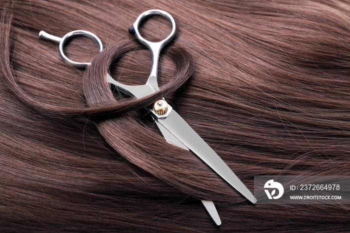 Hairdressers scissors with dark brown hair, close up