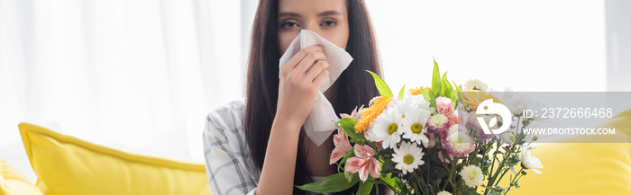 过敏妇女在鲜花旁用纸巾擦鼻子，横幅