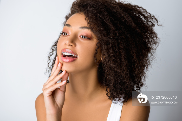 cheerful african american girl with dental braces, isolated on grey