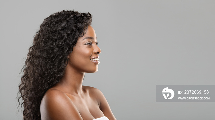 Beautiful black girl looking aside at copy space on gray background