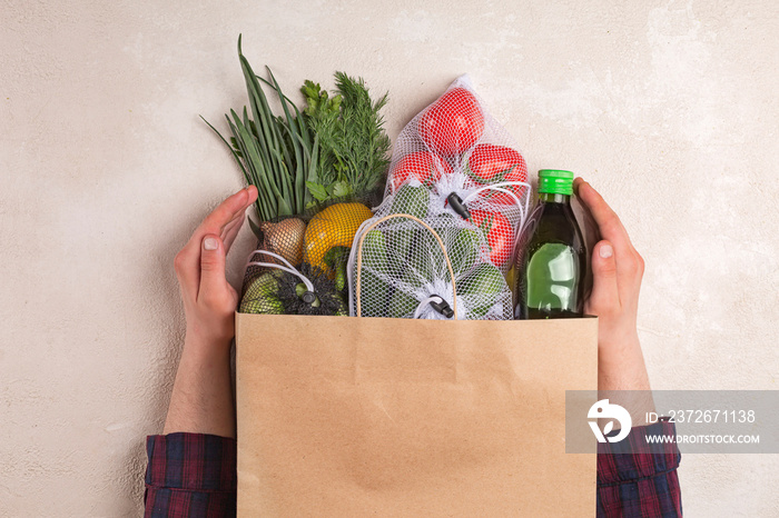 Man holds products in a paper bag. Vegetables in the range of shopping in the terrestrial and online