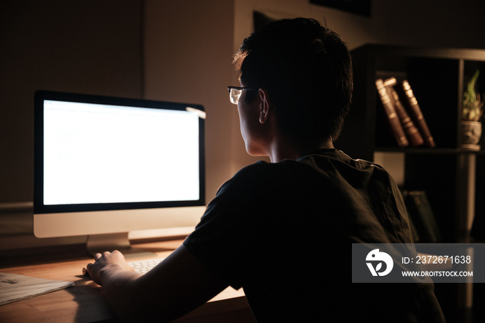 Serious man working with blank screen computer at nighttime