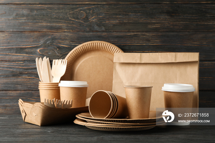 Eco - friendly tableware and paper bag on wooden table, copy space