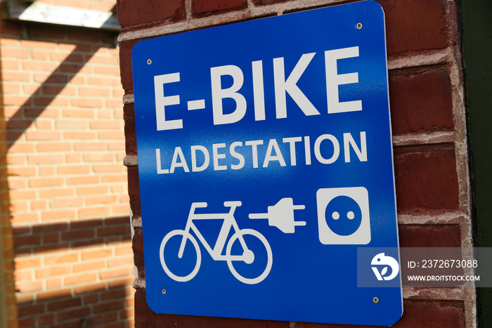 Isolated blue and white sign on brick wall with information for e-bike charging station (german word