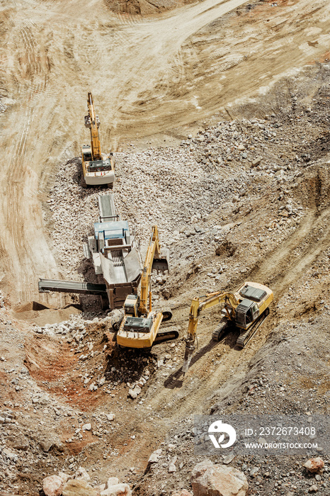 重型机械挖掘机在采石场工作，将石头和花岗岩装载到自卸卡车上。Bird ey