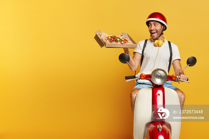 Responsible pizza delivery guy looks with overjoyed face expression at tasty snack, wants to eat, wo
