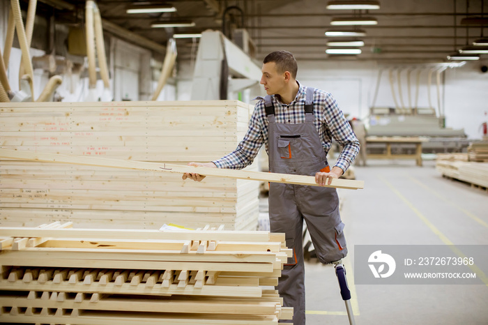 Disabled young man with an artificial leg is working at the furniture  factory