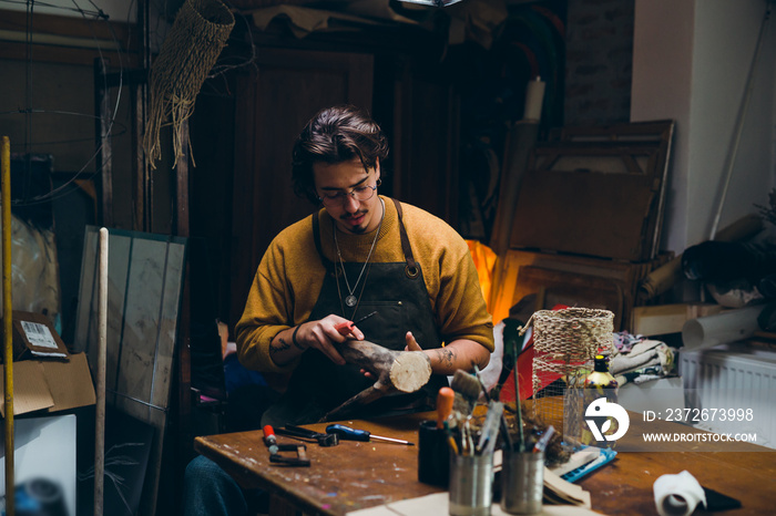 man sitting in his workshop and making artwork from wood