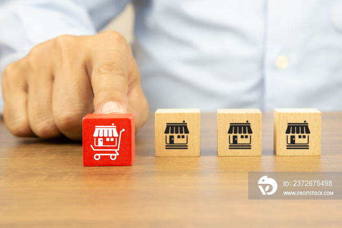 Close-up hand chooses cube wooden toy blocks stack with franchise business store icon in the shoppin