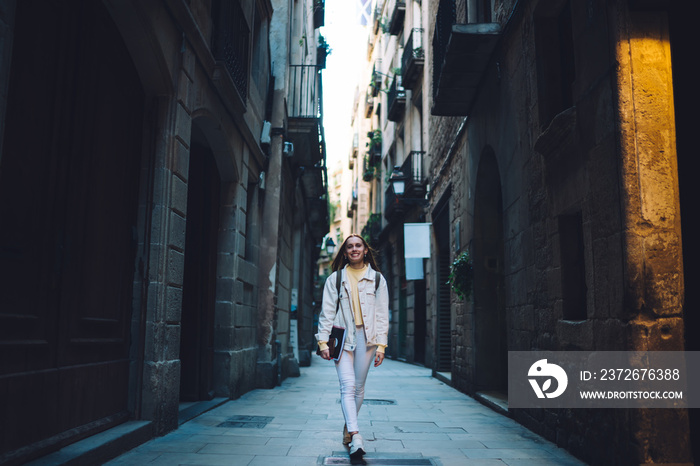 Cheerful modern female student walking along street