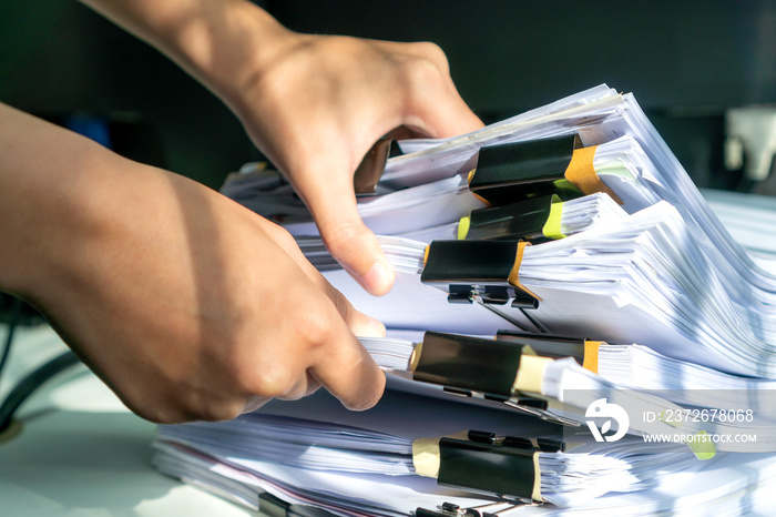 Businesswoman working in stacks of paperwork files for searching infomation unfinished documents abo