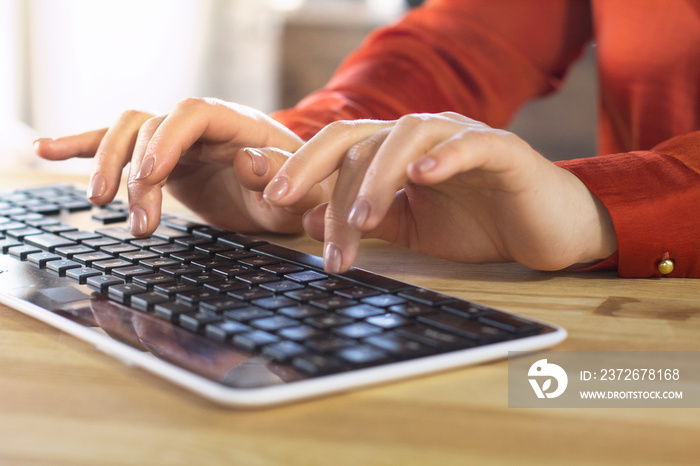 Womans hands on pc wireless keyboard. Gentle female hands with nude manicure slightly lifted above k